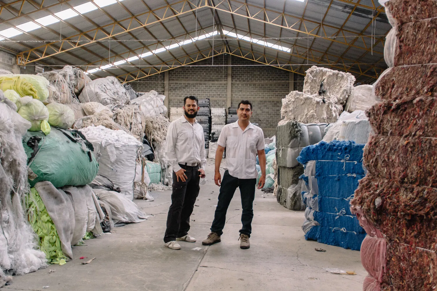 Equipo de ALBOMY entre pacas de material textil reciclado en la planta.